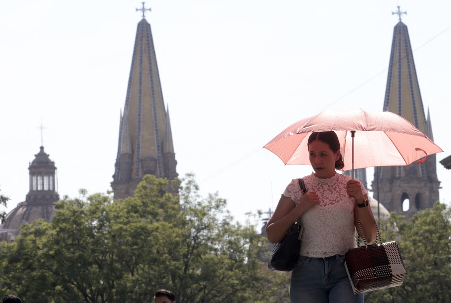 Mulher usa guarda-chuva para se proteger do sol durante uma onda de calor que atingiu Guadalajara, no México