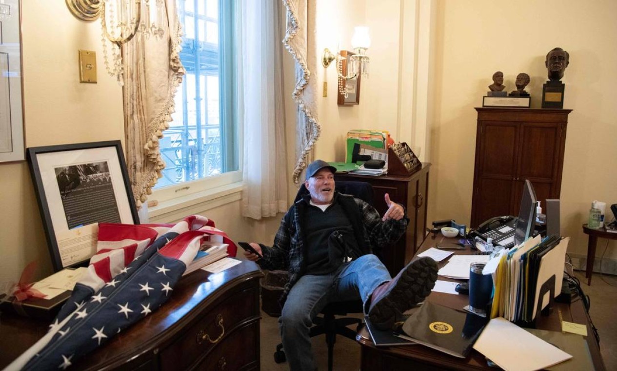 Um manifestante senta-se no gabinete da presidente da Câmara, Nancy Pelosi, durante invasão ao prédio do Capitólio  — Foto: SAUL LOEB / AFP
