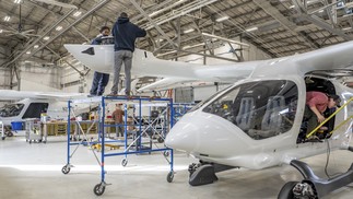 Funcionários da Beta Technologies trabalhando em dois aviões elétricos, um que decola como um avião convencional e outro que decola e aterrissa como um helicóptero, em uma instalação em Plattsburgh, N.Y. — Foto: Tony Cenicola/The New York Times