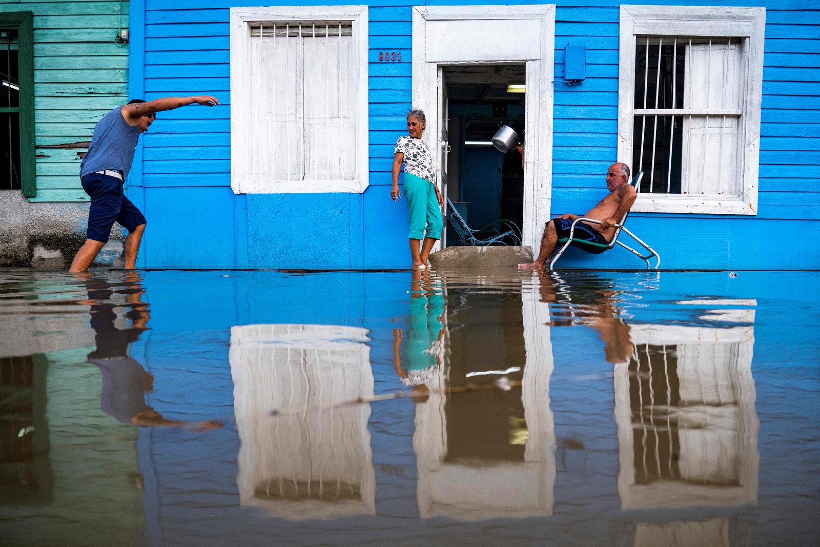 Um casal permanece fora de sua casa em uma área inundada de Batabano, província de Mayabeque, Cuba — Foto: Yamil LAGE/AFP