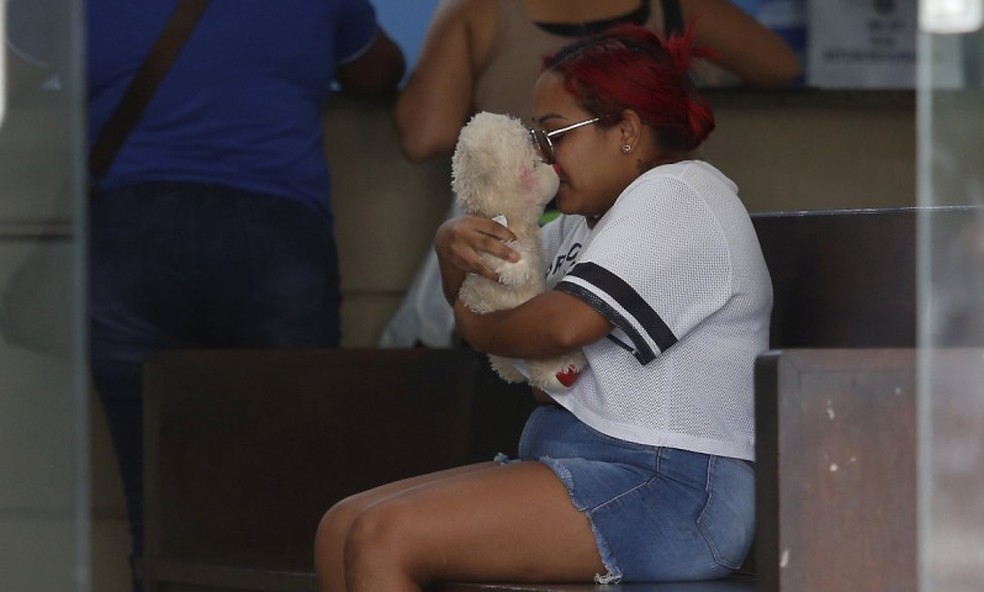 A mãe da Ester, abraçada ao urso de pelúcia da filha, aguarda no IML — Foto: Fabiano Rocha