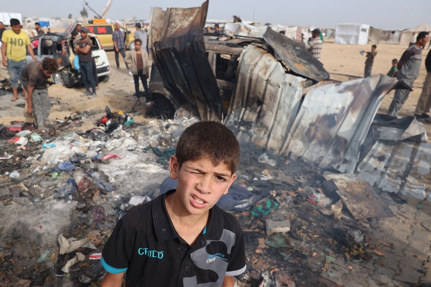 Menino palestino ao lado de barraca incendiada em Rafah