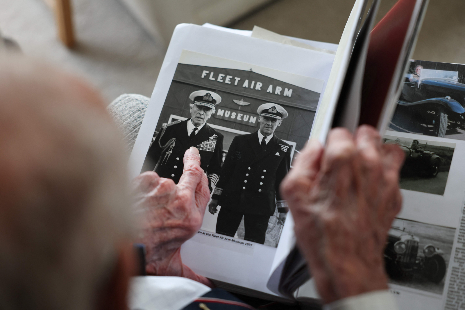 O ex-oficial da Marinha Real britânica e veterano do Dia D, contra-almirante John Roberts, olha um álbum de fotos contendo fotos de seu serviço durante a Segunda Guerra Mundial, na sala de sua casa em Whitstable, Kent — Foto: Daniel LEAL / AFP