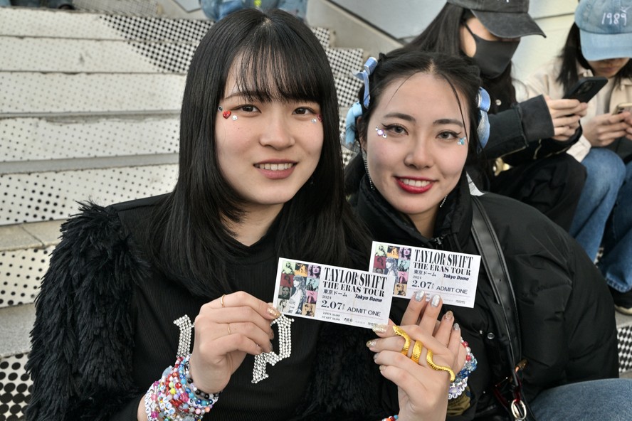 Fãs de Taylor Swift, também conhecidos como Swifties, posam com seus ingressos em frente ao Tokyo Dome, algumas horas antes da do primeiro show da 'Eras Tour' em Tóquio