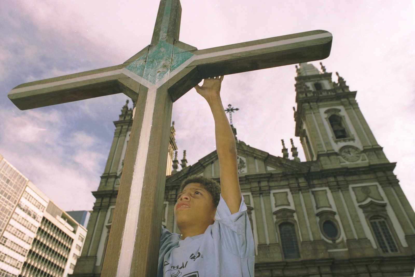 Menino toca a cruz instalada na Candelária para lembrar as vítimas da chacina, durante ato em julho de 1995  — Foto: Domingos Peixoto