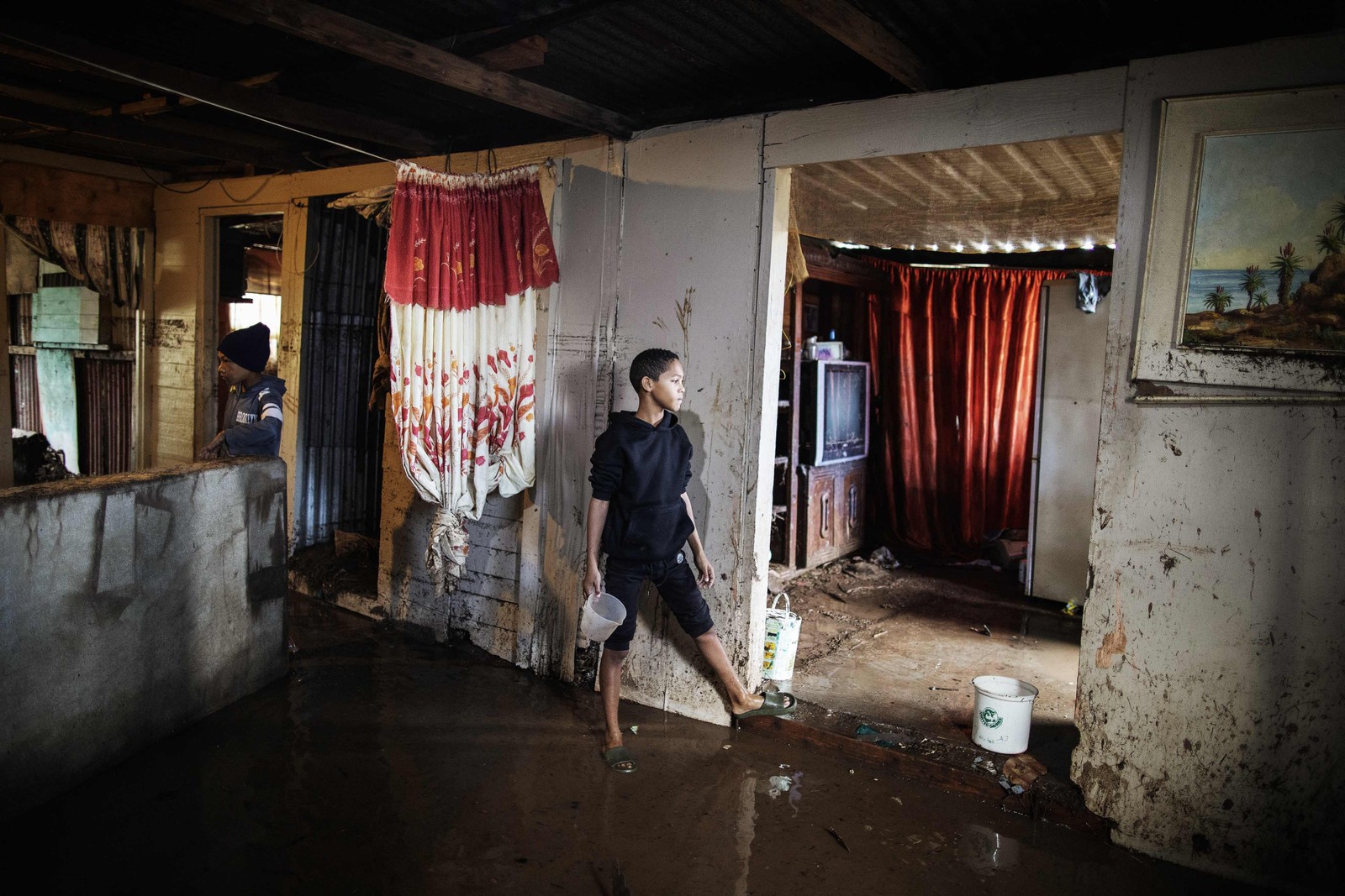 Moradores limpam as águas das enchentes de suas casas. As enchentes causadas por chuvas torrenciais e ventos fortes na costa leste da África do Sul mataram pelo menos 22 pessoas, disseram as autoridades locais na terça-feira. As inundações atingiram vários locais em duas províncias do leste, dois raros tornados foram detectados, as temperaturas caíram e a neve caiu em algumas regiões centrais. — Foto: GIANLUIGI GUERCIA/AFP