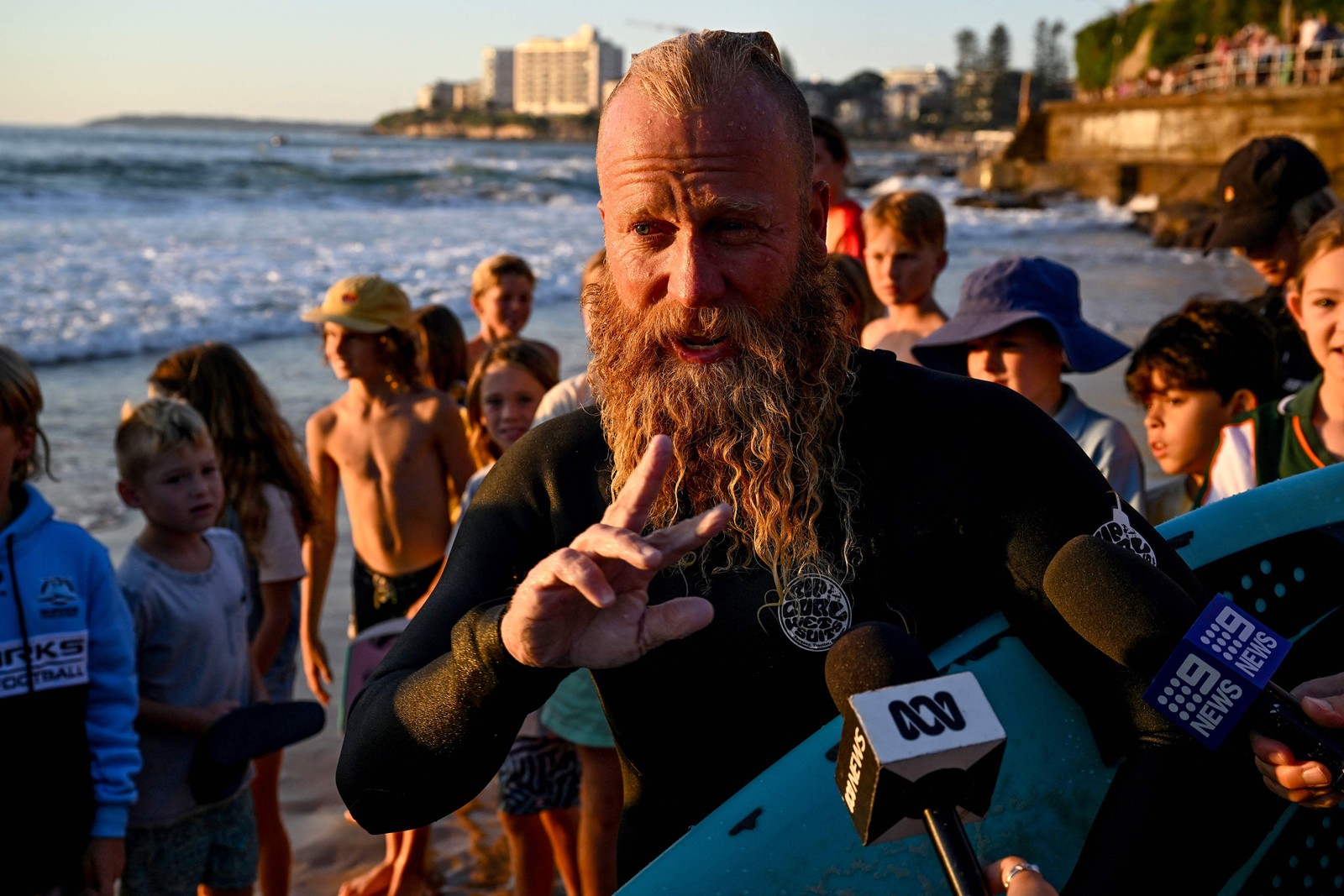 O ex-surfista profissional australiano Blake Johnston fala à mídia depois de quebrar o recorde da sessão de surf mais longa do mundo em Cronulla Beach, em Sydney, em 17 de março de 2023 — Foto: Saeed Khan / AFP