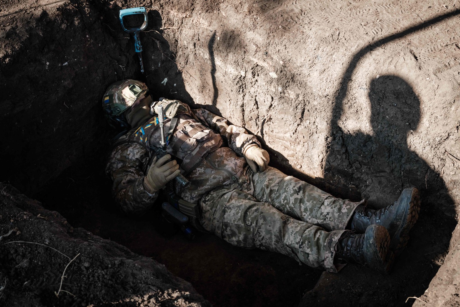 Soldado ucraniano descansa em trincheira recém-cavada enquanto companheiros disparam contra posição rua próximo em Bakhmut — Foto: YASUYOSHI CHIBA/AFP