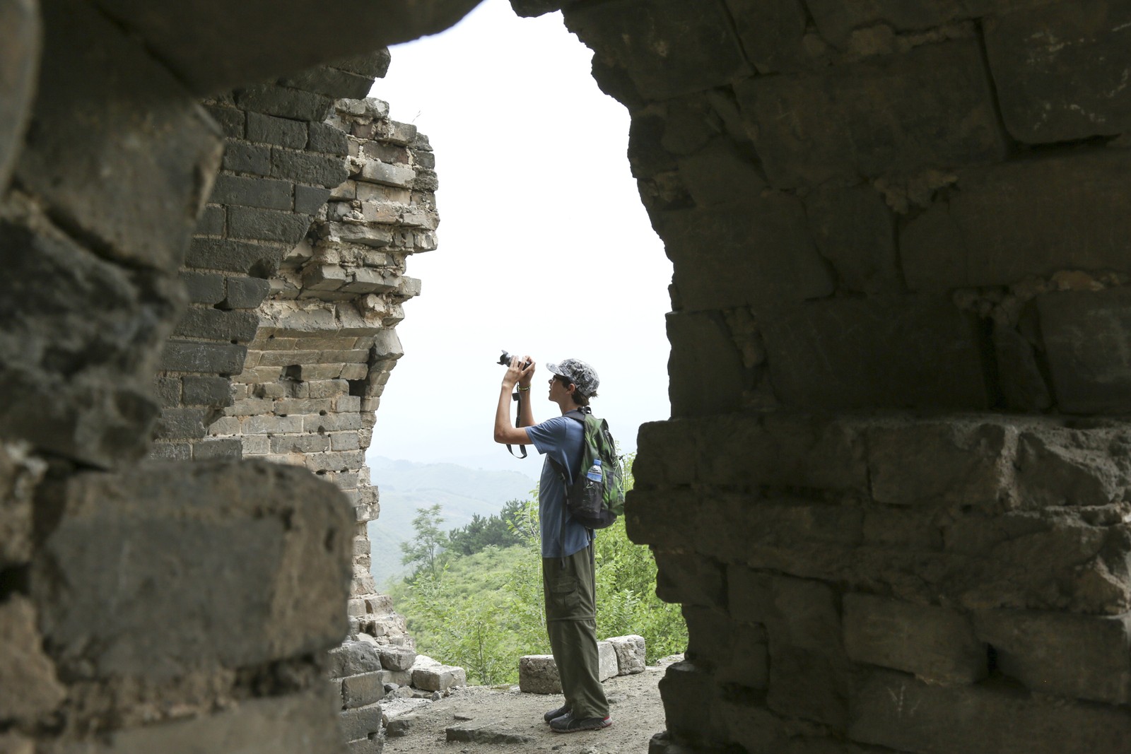 Jovem tira uma foto de um arco em ruínas em uma torre de vigia ao longo da Grande Muralha da China — Foto: Robb Kendrick/The New York Times