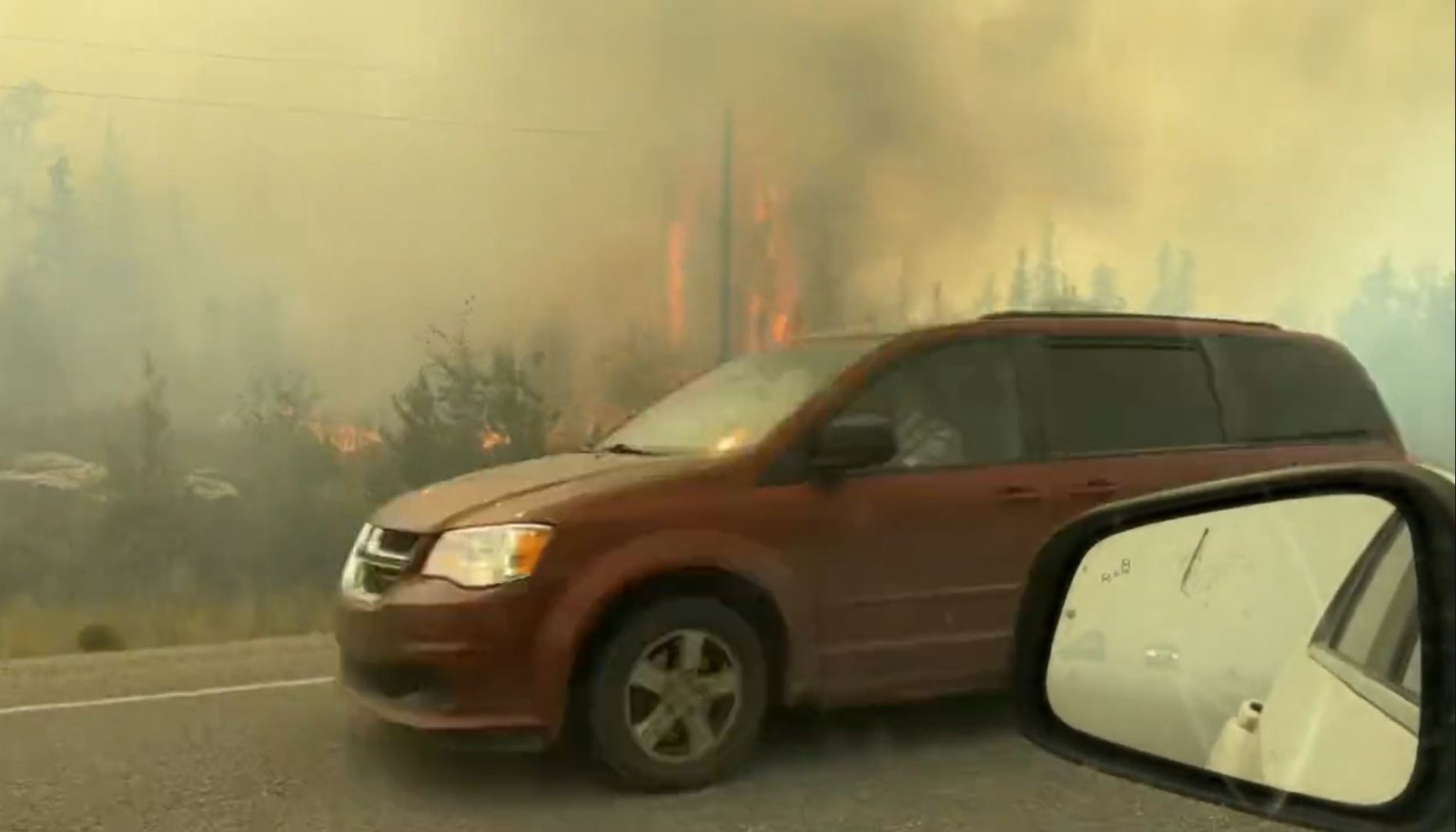 Imagem mostra veículos dirigindo na rodovia enquanto as pessoas figem de Yellowknife, no Canadá — Foto: Jordan Straker / UGC / AFP