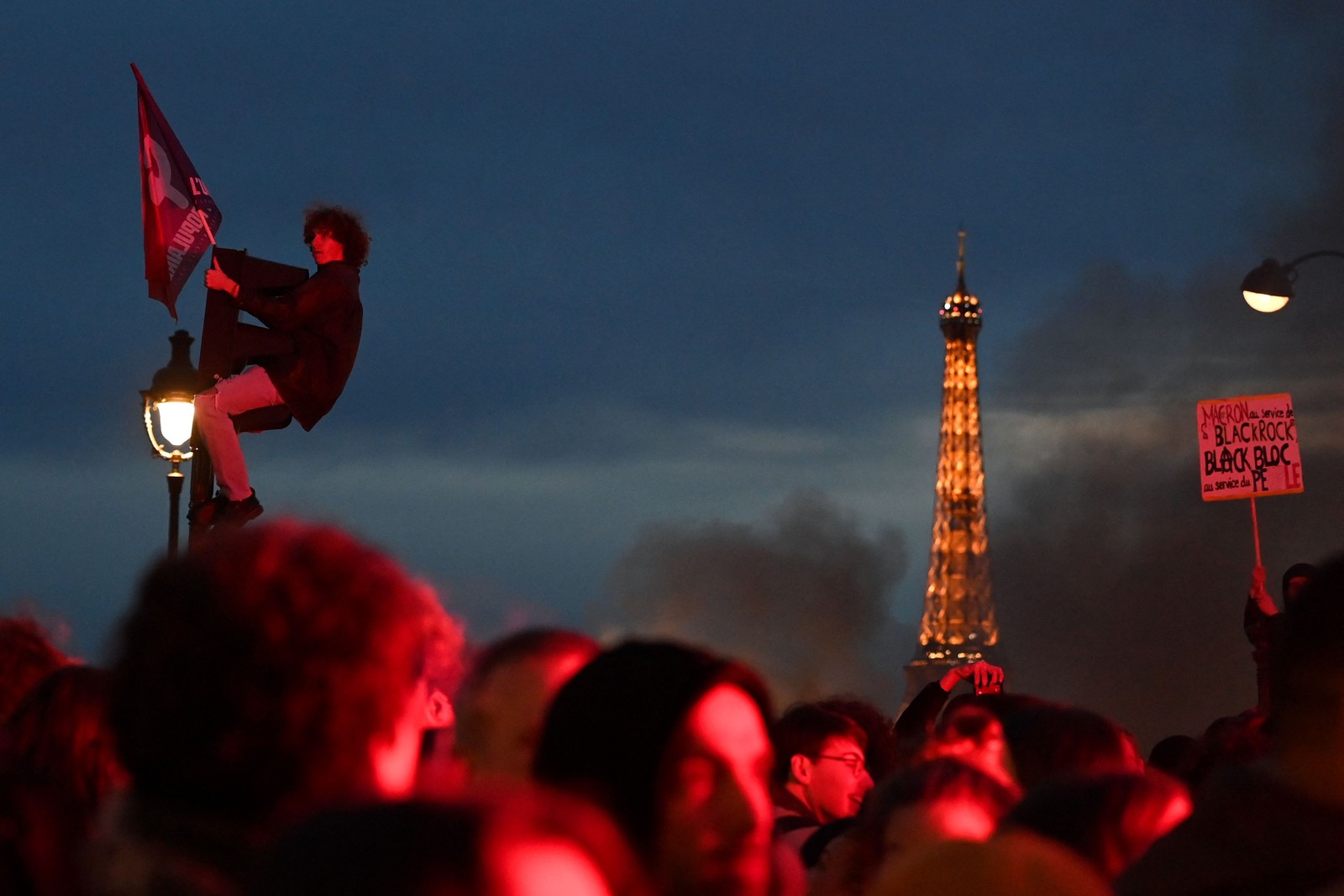 Manifestante sobe em semáforo no centro de Paris durante revolta pela aprovação da reforma da previdência na França — Foto: ALAIN JOCARD/AFP