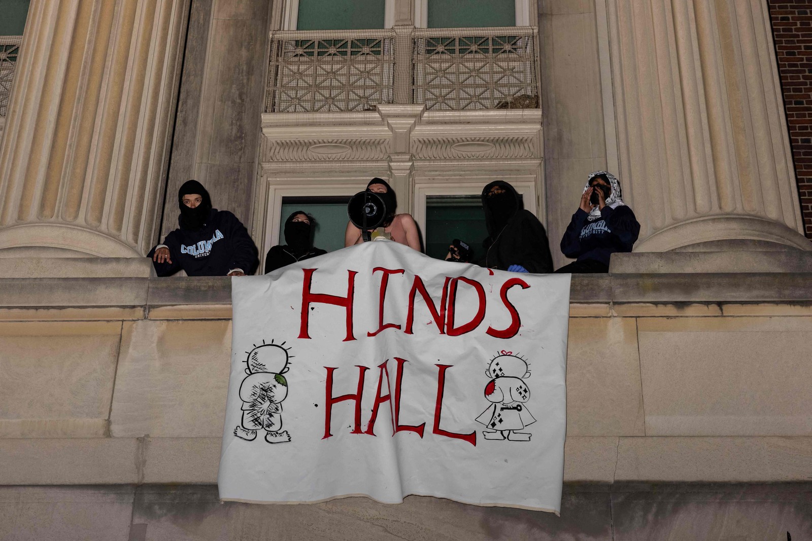 Manifestantes do acampamento pró-Palestina no Campus de Columbia mostram uma faixa enquanto se barricam dentro do Hamilton Hall, onde está localizado o escritório do Reitor — Foto: Alex Kent/Getty Images/AFP