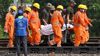 Equipes de resgate carregam o corpo de uma das vítimas ao longo dos trilhos no local do acidente de uma colisão de trens perto de Balasore, a cerca de 200 km da capital do estado, Bhubaneswar — Foto:  Dibyangshu SARKAR / AFP