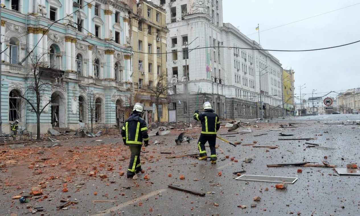 Bombeiros caminham entre os danos após o bombardeio das forças russas na Praça da Constituição, em Kharkiv, a segunda maior cidade da Ucrânia, em 2 de março  — Foto: SERGEY BOBOK / AFP