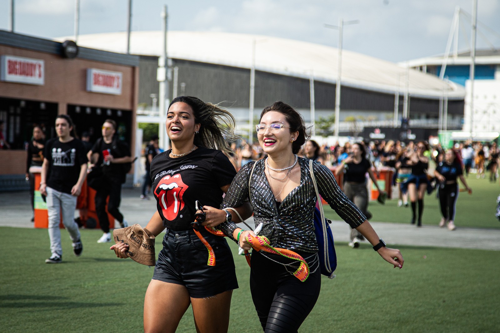 Amigas correm para garantir um lugar na grade, no segundo dia de festival — Foto: Hermes de Paula/Agência O Globo