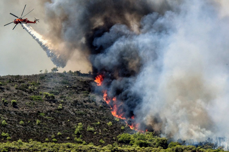 Um helicóptero tenta conter incêndio derivado de nova onda de calor que atinge o Hemisfério Norte