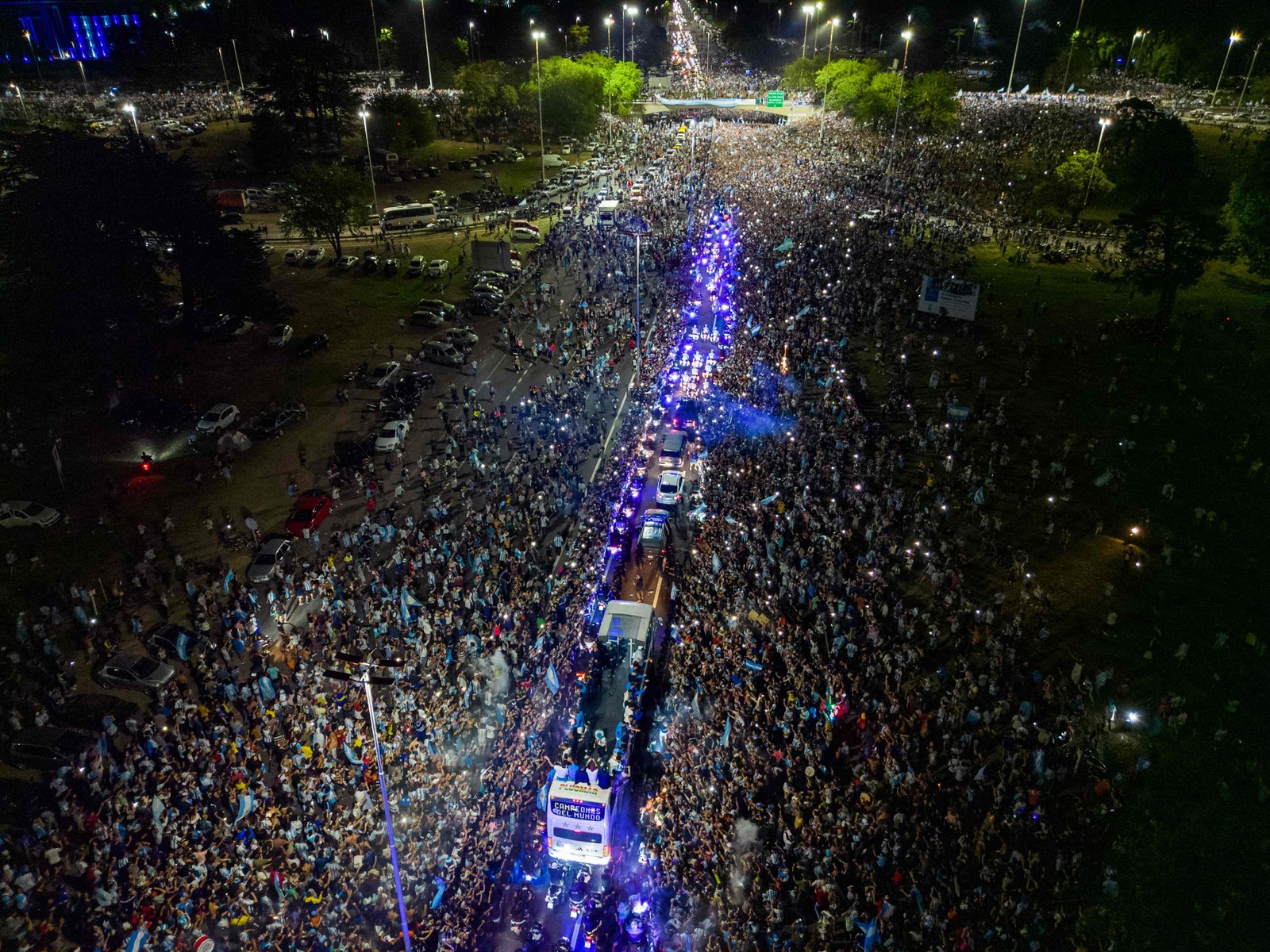 imagem aérea tirada em 20 de dezembro de 2022 mostra os jogadores da Argentina comemorando a bordo de um ônibus com torcedores depois de vencer a Copa do Mundo ao deixar o Aeroporto Internacional de Ezeiza — Foto: TOMAS CUESTA/ AFP