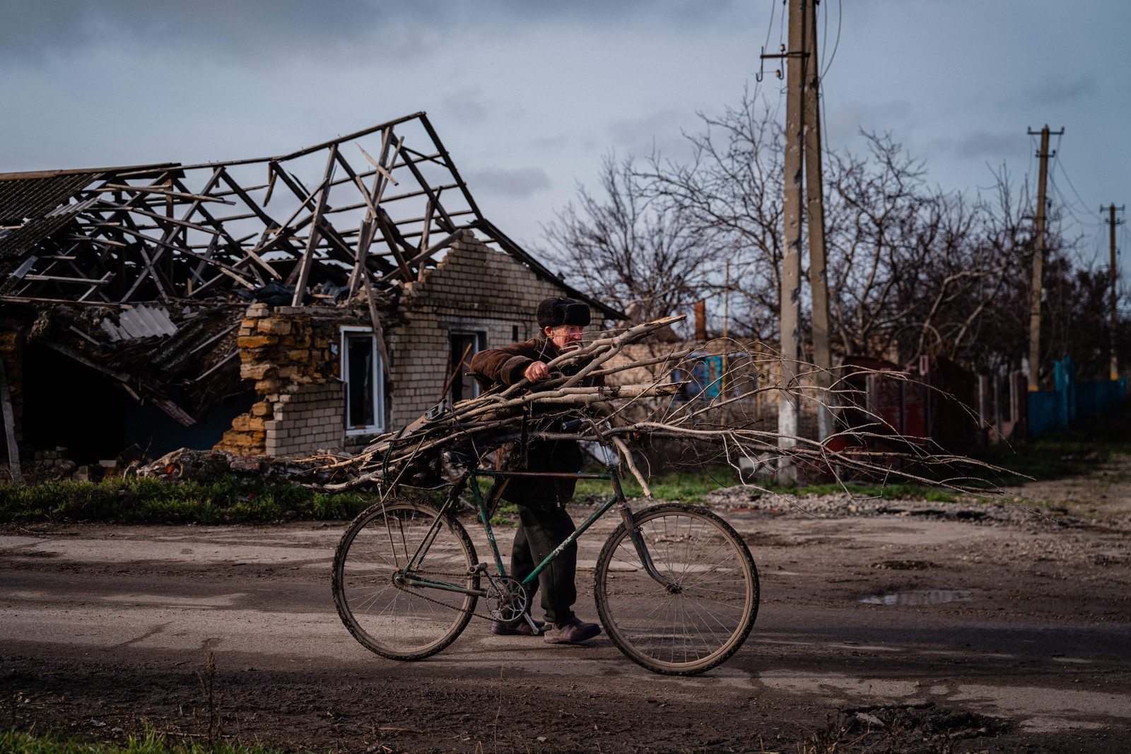 Volodymyr Kovalov, 77 anos, carrega lenha para aquecer o ambiente e cozinhar na vila de Posad-Pokrovs'ke, região de Kherson, Ucrânia — Foto: DIMITAR DILKOFF/AFP