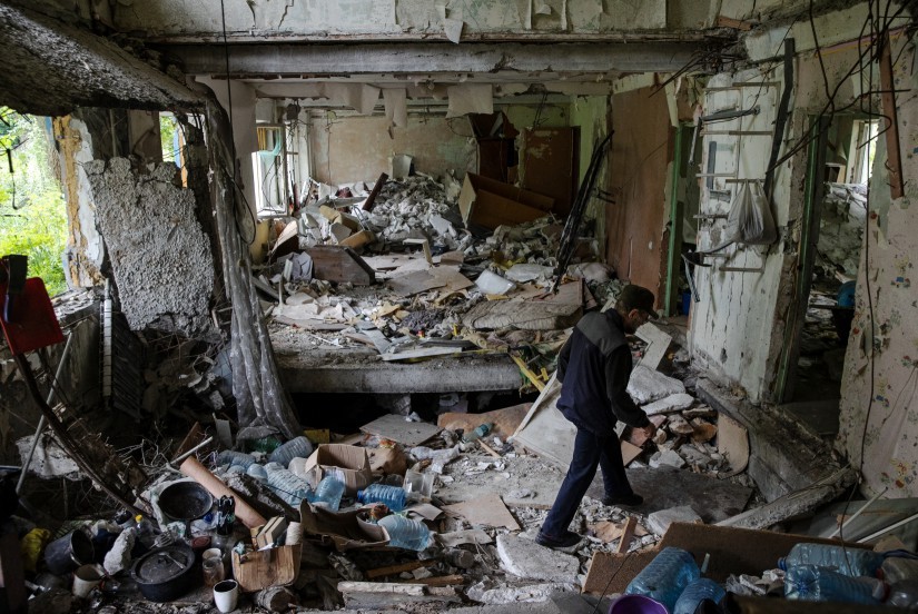 Serhiy Albertovych, último residente de sua rua, caminha entre um prédio danificado — Foto: New York Times