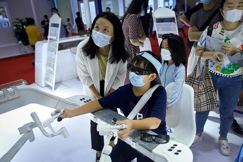 Uma criança opera um braço robótico utilizando em cirurgias durante a Conferência Mundial, que acontece até domingo em Pequimirurgia — Foto: Wang Zhao / AFP