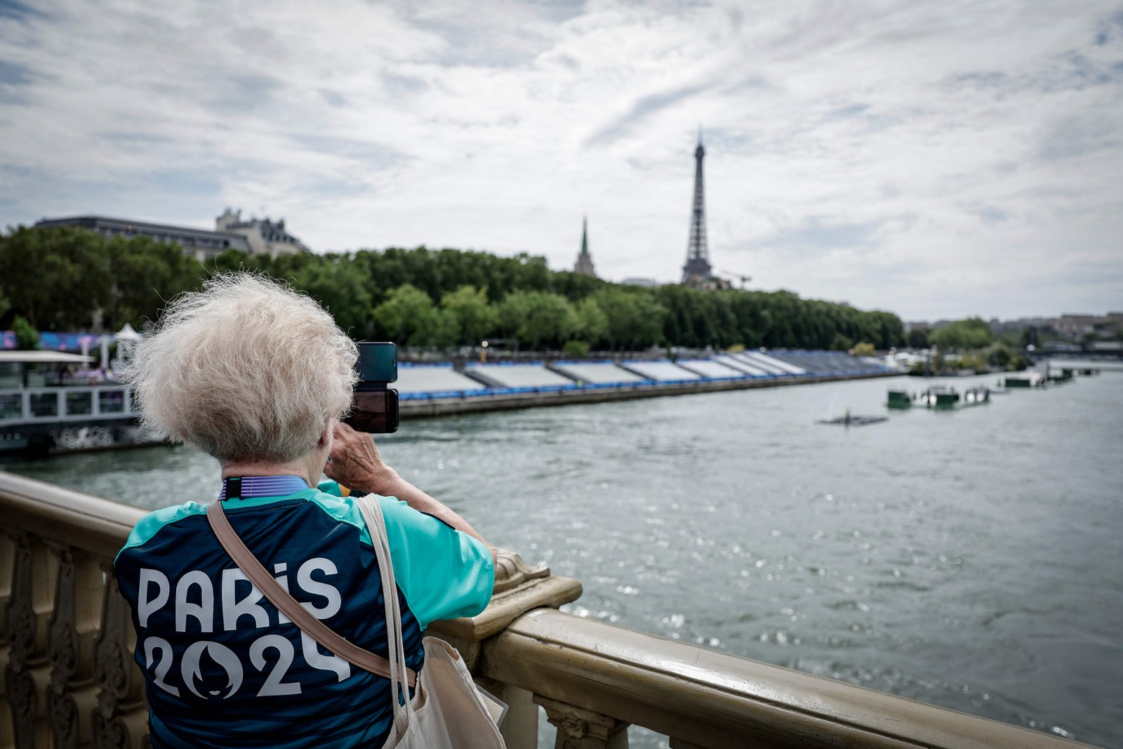 Mulher observa preparação do Rio Sena para abertura de Paris-2024 — Foto: AFP