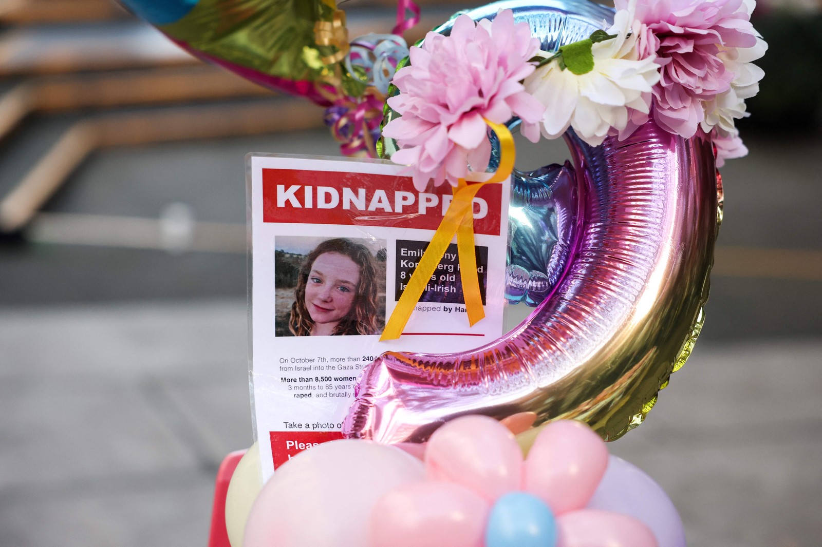 Cartaz que retrata a menina irlandesa-israelense Emily Hand, mantida refém pelo Hamas em Gaza, é exibido perto de um balão durante uma reunião para seu aniversário de 9 anos — Foto: Daniel LEAL / AFP