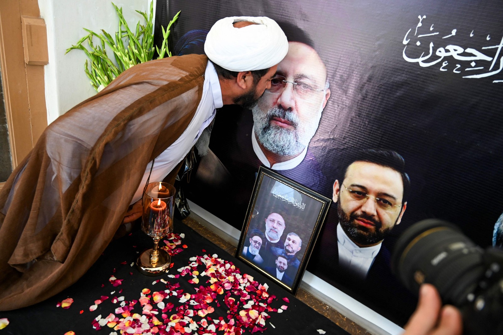 Um homem beija o retrato do presidente iraniano Ebrahim Raisi, que morreu em um acidente de helicóptero, durante uma cerimônia de condolências realizada no Centro Cultural Iraniano em Peshawar, em 21 de maio de 2024. — Foto: Abdul MAJEED / AFP