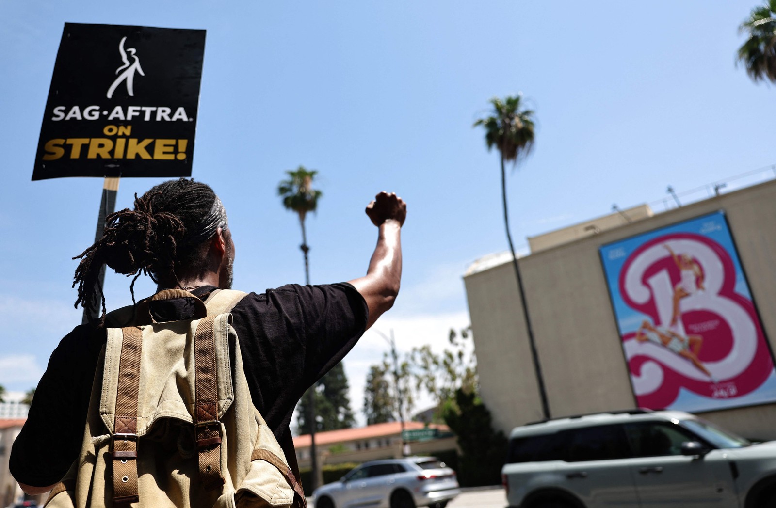 James Mathis III, membro do SAG-AFTRA em greve, protesta do lado de fora dos estúdios da Warner Bros, em frente ao cartaz do filme 'Barbie' — Foto: Mario Tama/Getty Images/AFP