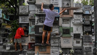 Homens limpam um cemitério em Manila, Filipinas, como preparativos do Dia de Todos os Santos em 1º de novembro — Foto: JAM STA ROSA/AFP