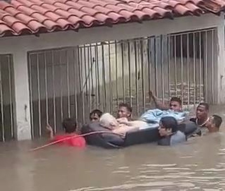 Idoso é levado por grupo em alagamento durante chuva no Rio — Foto: Reprodução/Arquivo Pessoal