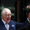 O rei Charles III acena e balança um buquê de flores durante sua visita ao Centro de Câncer Macmillan do Hospital Universitário de Londres. - HENRY NICHOLLS/AFP