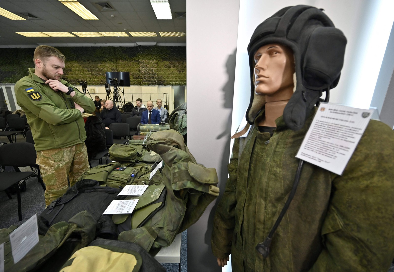 Oficial ucraniano examina equipamentos e suprimentos de invasores russos, apreendidos pelas forças ucranianas e exibidos antes de um briefing dos representantes das Forças de Segurança e Defesa ucranianas no centro de mídia militar, em Kiev. — Foto: Genya SAVILOV / AFP