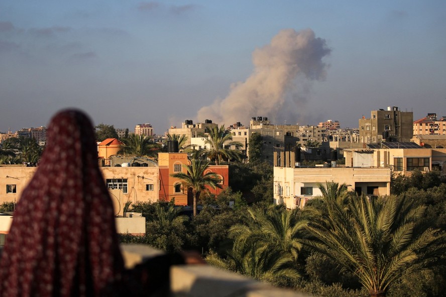 Mulher palestina observa de longe bombardeio na região de al-Zawaida, centro de Gaza