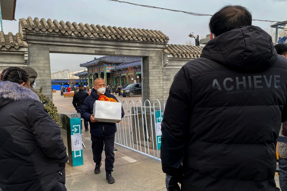 Homem carrega urna com cinzas de parente morto, em Pequim — Foto: Noel Celis / AFP