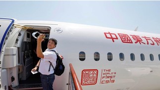 Passageiro tira um self ao embarcar no primeiro jato de passageiros produzido na China, o C919  — Foto: AFP