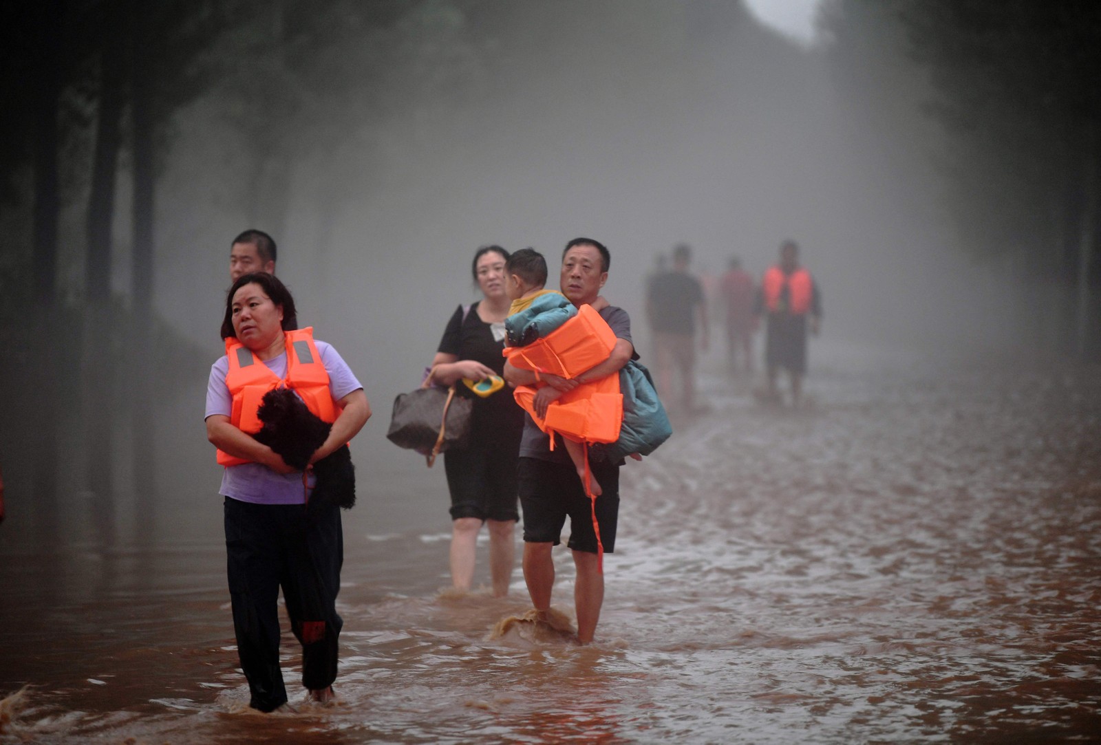 Pessoas deixam uma área inundada após fortes chuvas em Zhuozhou, na província de Hebei, no norte da China.  — Foto: CNS / AFP / China OUT