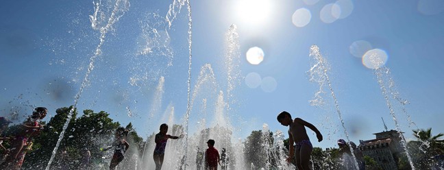 Crianças se refrescam em uma fonte em Colmar, leste da França, enquanto país enfrenta onda de calor, cruzando a marca de 40°C . — Foto: SEBASTIEN BOZON / AFP