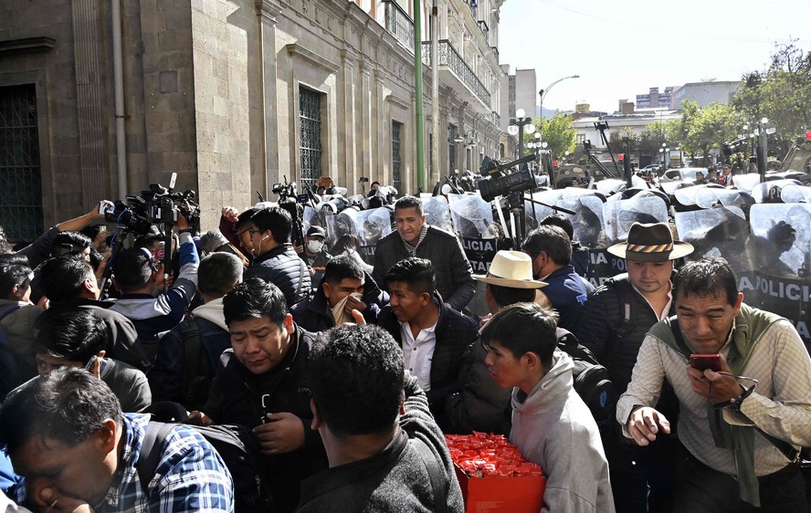 Pessoas se afastam do gás lacrimogêneo disparado por tropas militares em frente ao Palácio Quemado, na Plaza de Armas, em La Paz