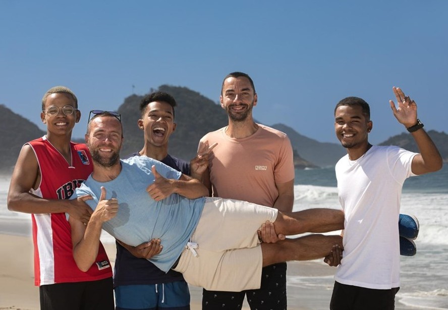 Em Copacabana, os cariocas Kauã (de vermelho), Willian (de azul) e Rodrigo (de branco), carregam um dos pais franceses, Guillaume, com a ajuda do outro, Olivier: história com final feliz