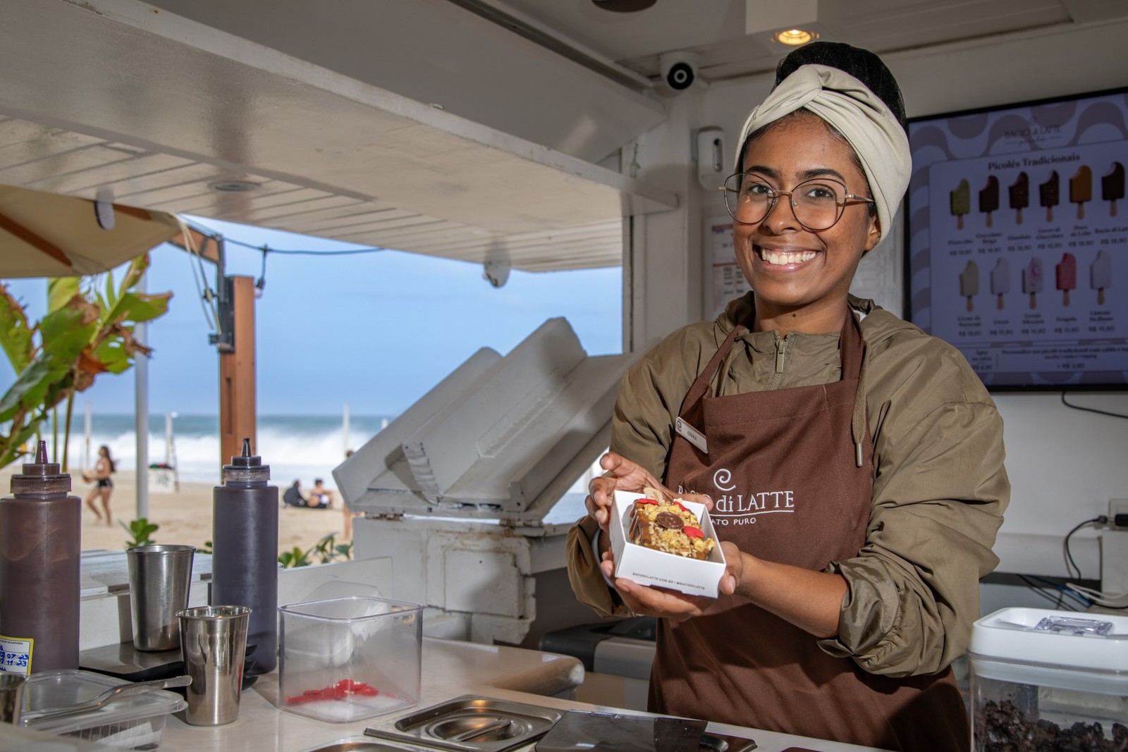 Gelaterias trabalham com café da manhã, sorvetes para cães e picolés personalizados. No quiosque da Bacio di Latte, na orla de Ipanema, a funcionária Erika dos Santos prepara sorvetes personalizados — Foto: Ana Branco/Agência O Globo