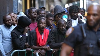 Refugiados recém-chegados aguardam do lado de fora do Hotel Roosevelt, que foi transformado em um centro de recepção de imigrantes, para tentar garantir moradia temporária.  — Foto: TIMOTHY A. CLARY / AFP