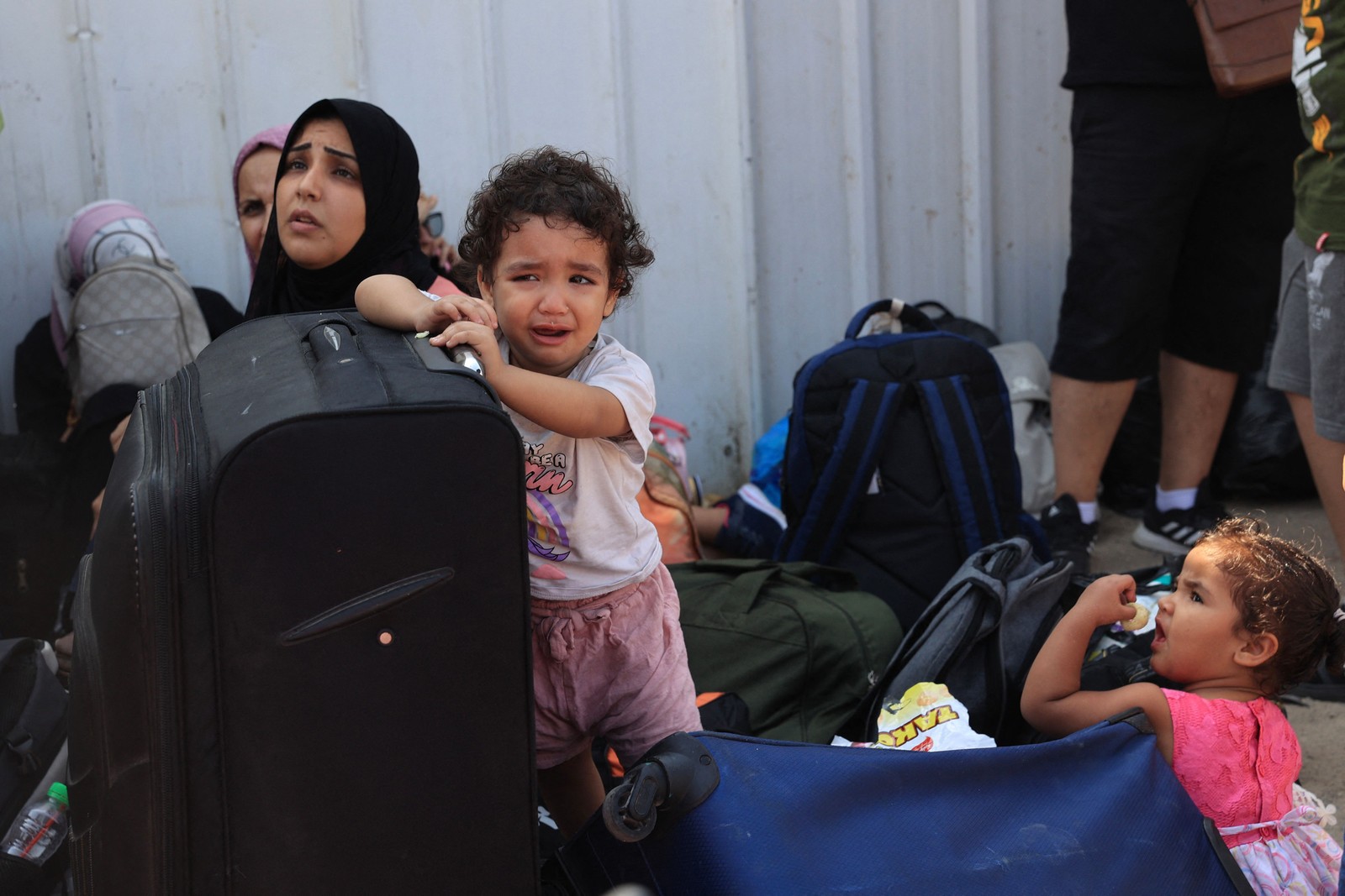 Família palestina espera com malas e crianças na passagem de Rafah — Foto: Said Khatib/AFP