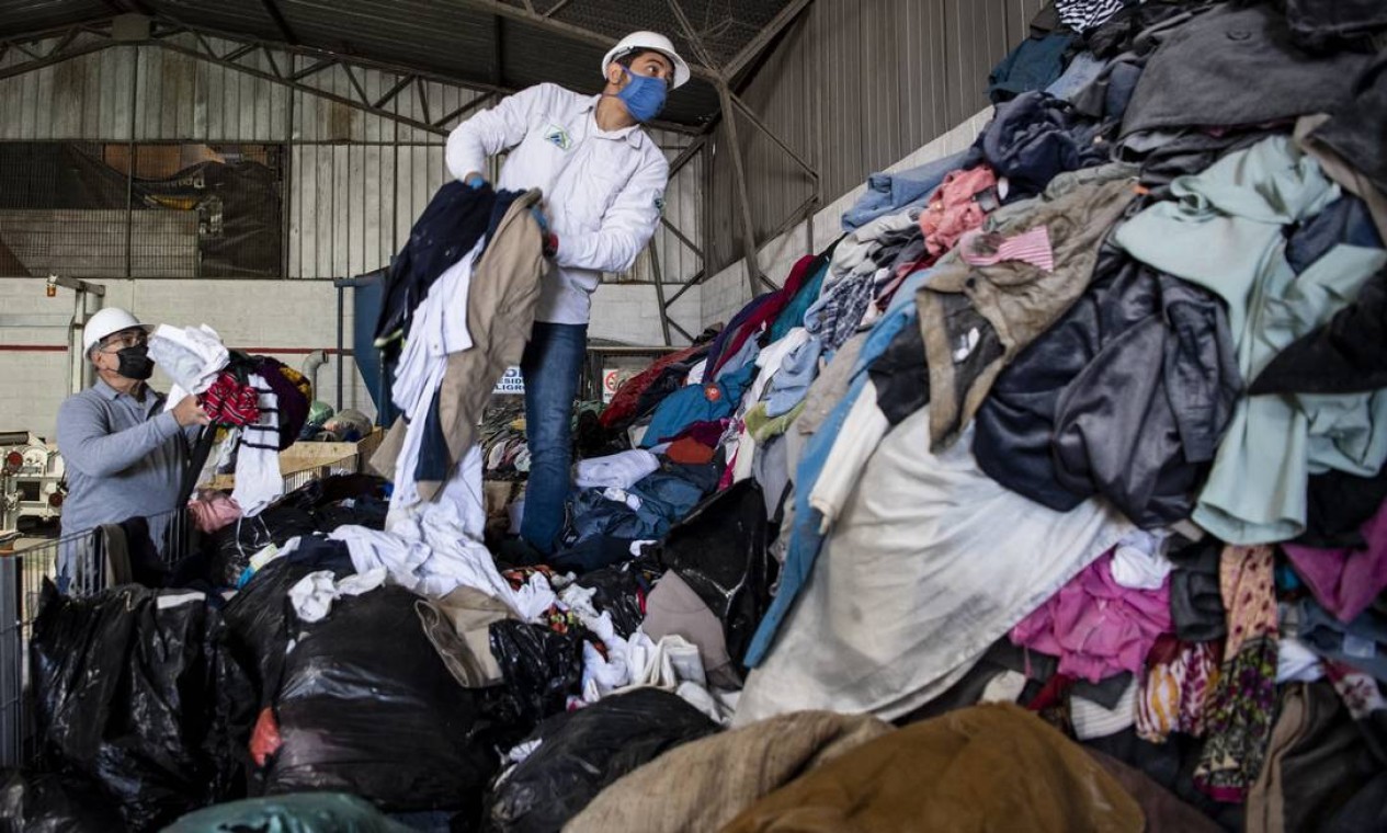 Homem trabalha em uma fábrica que recicla roupas usadas descartadas no deserto do Atacama  — Foto: MARTIN BERNETTI / AFP