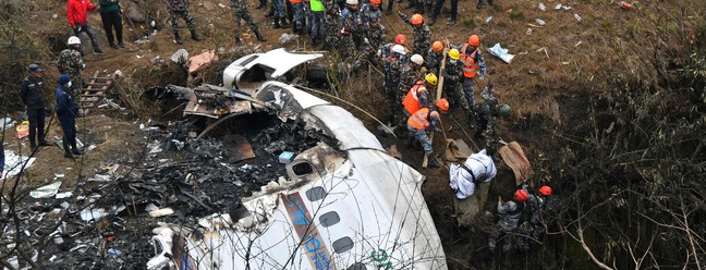 Equipes de resgate retiram corpo de uma vítima da queda de um avião da Yeti Airlines em Pokhara, Nepal — Foto: PRAKASH MATHEMA / AFP