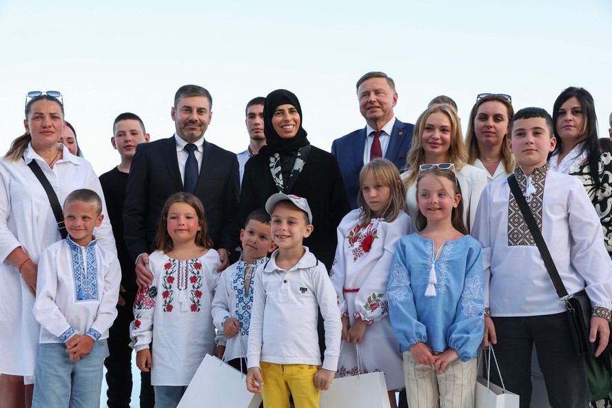 A Ministra de Estado para Cooperação Internacional do Catar, Lolwah Al-Khater, e o Comissário de Direitos Humanos no Parlamento Ucraniano, Dmytro Lubinets, posam para foto com crianças ucranianas e suas famílias em Doha, após acordo com a Rússia