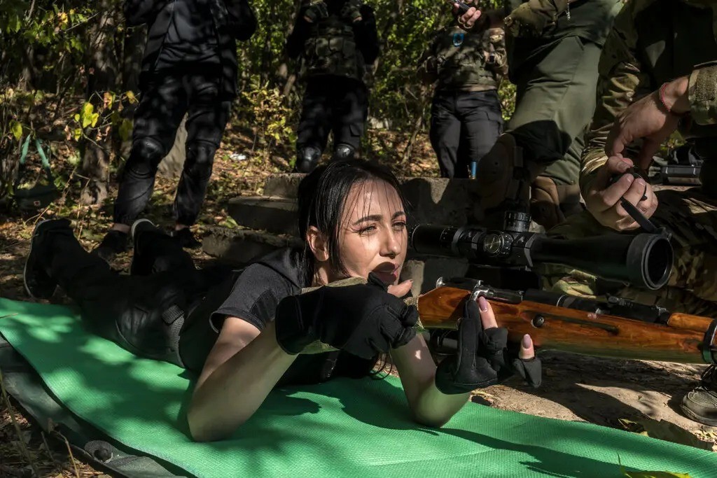 Iryna Sychova, gerente de compras de uma loja de departamentos, aprendendo a mirar um rifle de precisão — Foto: Brendan Hoffman / New York Times