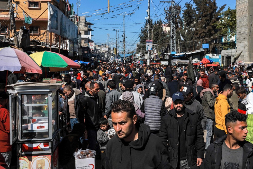 Pessoas caminham em uma rua principal lotada em Rafah, no sul da Faixa de Gaza — Foto: Mohammed ABED / AFP