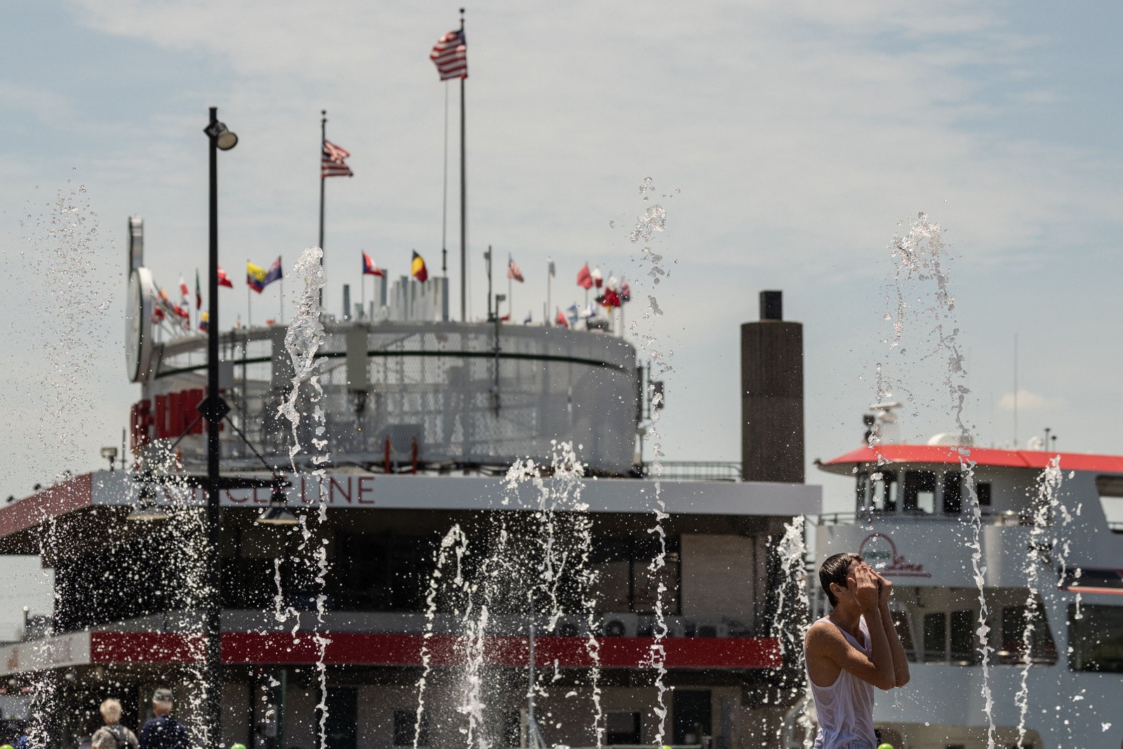 Pessoas se refrescam em uma fonte perto do rio Hudson durante uma onda de calor  na cidade de Nova York. O calor mortal que cobriu recentemente os EUA, o México e a América Central tornou-se 35 vezes mais provável devido ao aquecimento global, disseram cientistas climáticos da World Weather Attribution (WWA) em 20 de junho. — Foto: Yuki IWAMURA / AFP