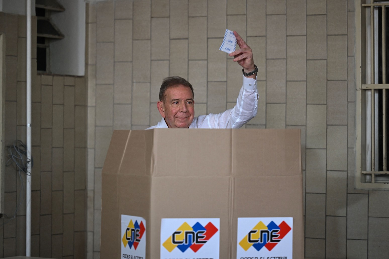 O candidato presidencial da oposição venezuelana Edmundo Gonzalez Urrutia mostra sua cédula enquanto vota na escola Santo Tomas de Villanueva em Caracas durante a eleição presidencial em 28 de julho de 2024. — Foto: Photo by RAUL ARBOLEDA / AFP