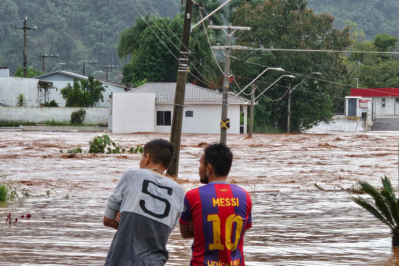 Pessoas observam uma rua inundada após fortes chuvas em Encantado, Rio Grande do Sul. Pelo menos dez pessoas morreram e 21 estão desaparecidas devido às fortes chuvas no estado. — Foto: Gustavo Ghisleni/AFP